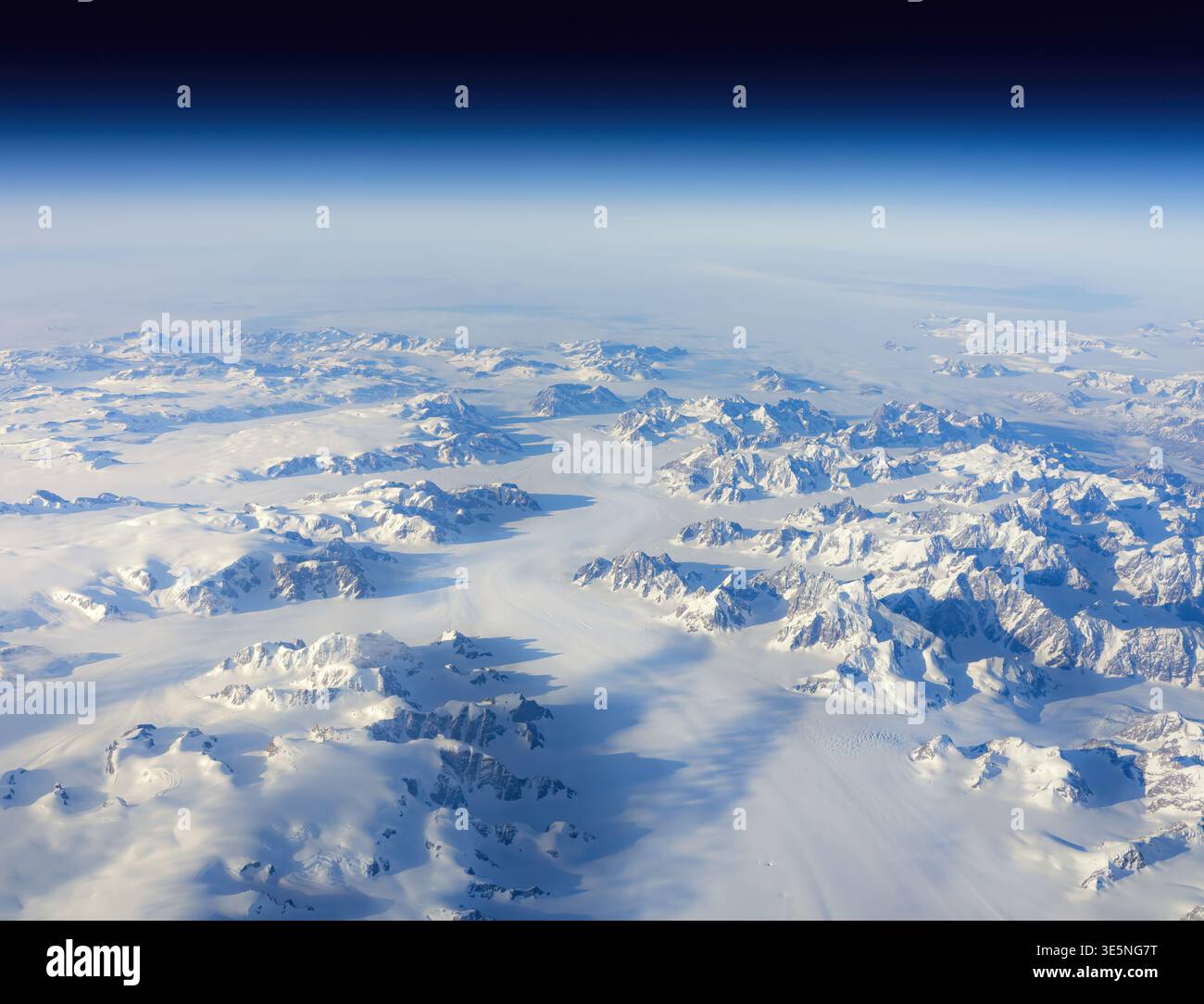 La vista aerea delle montagne bianche e delle valli glaciali incontra l'orizzonte nebuloso sotto un cielo blu profondo, Narsarsuaq, Groenlandia. Foto Stock