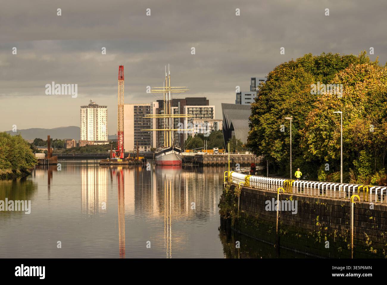 Il veliero Glenlee è ormeggiato all'esterno del Riverside Transport Museum sul fiume Clyde, incorniciato da moderni edifici sul lungomare, alberi autunnali e tranquillo refle Foto Stock
