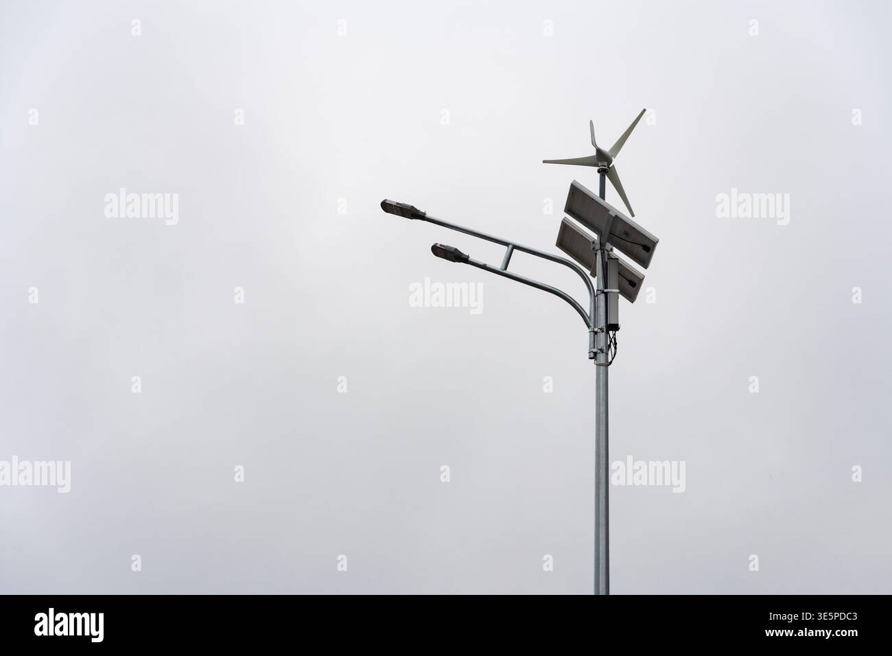 Palo per lampioni con pannelli solari e turbine eoliche che alimentano le lampade a LED, simboleggiano l'energia rinnovabile e la tecnologia urbana sostenibile Foto Stock