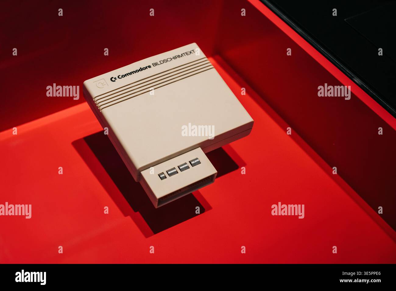 Modulo d'interfaccia vintage Commodore Bildschirmtext. Cartuccia decodificatrice beige classica con nervature, visualizzata su sfondo rosso. Foto Stock