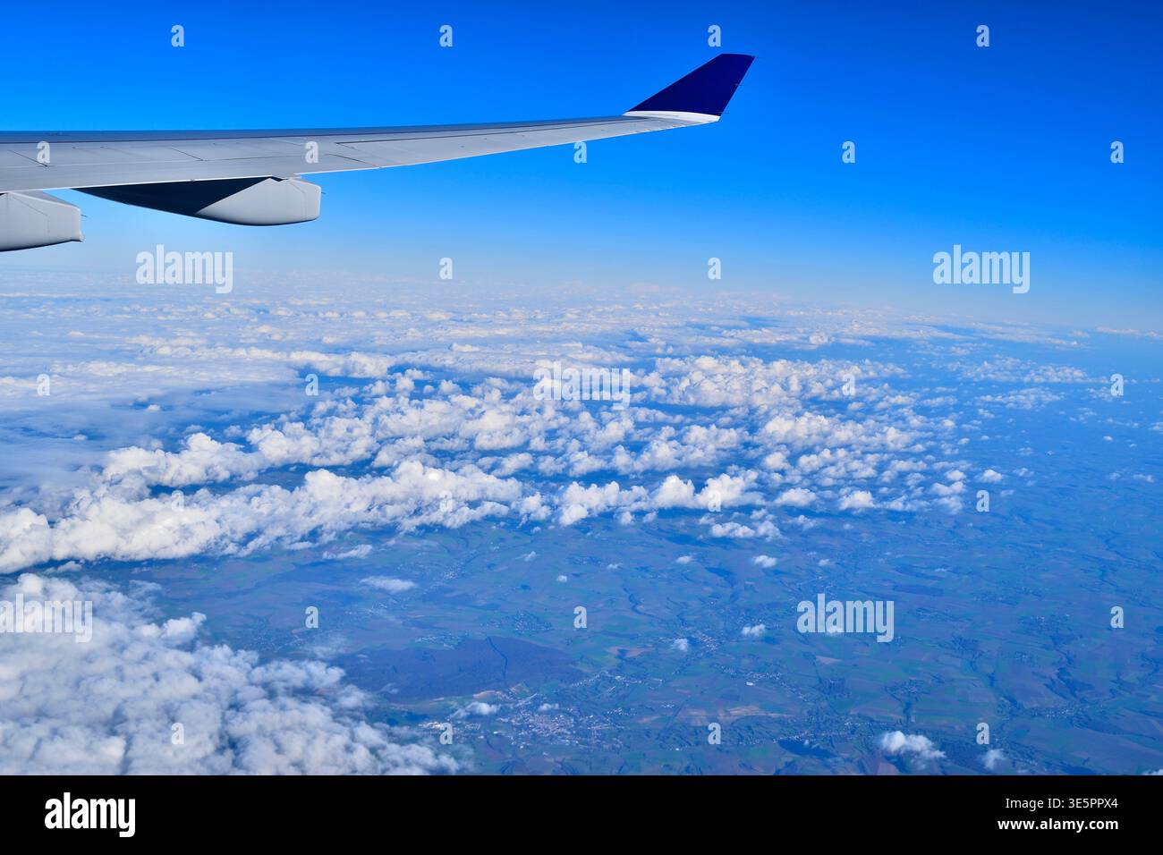 Una vista aerea mozzafiato attraverso la finestra di un aereo, che cattura il cielo blu profondo che si fonde con l'orizzonte terrestre durante un volo a lungo raggio Foto Stock