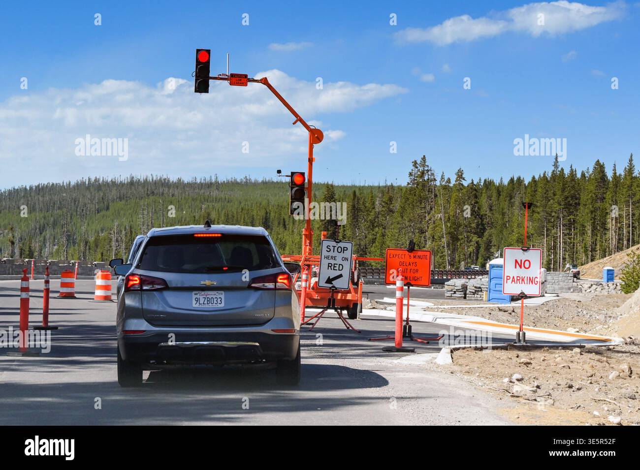 Yellowstone, Wyoming, Stati Uniti d'America - 1° giugno 2025: L'auto si fermò a un semaforo rosso per lavori di miglioramento della strada su una strada nel parco nazionale di Yellowstone. Foto Stock