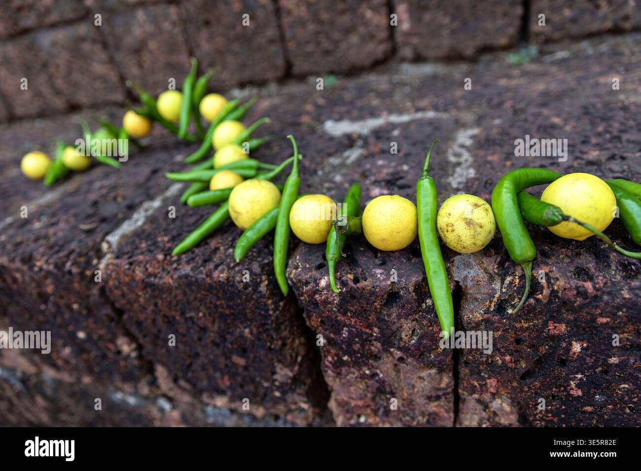 Oggetto rituale culturale Nimbu Mirchi appeso su una superficie di pietra ruvida in un tempio indù, Kerala, India Foto Stock
