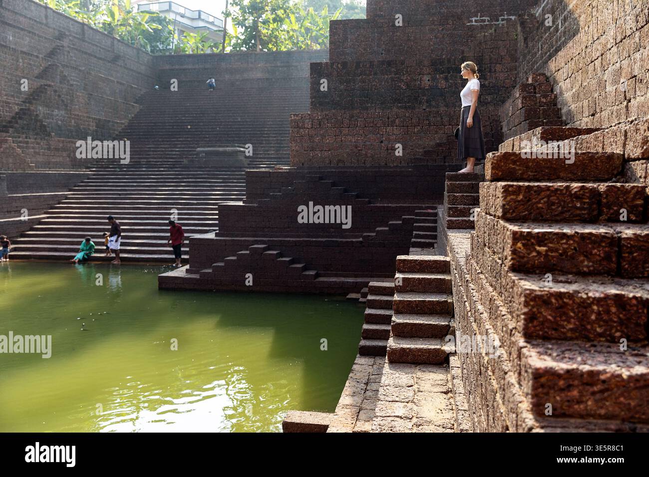 Turista donna che si erge sugli antichi gradini di pietra del tempio di Sree Peralassery nel Kerala, in India Foto Stock