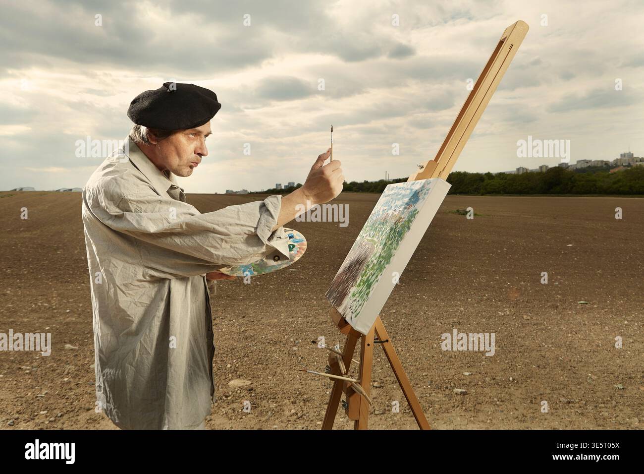 Uomo più anziano che dipinge opere d'arte su tela e scala di misurazione Foto Stock