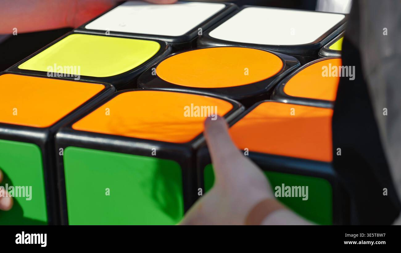Mani che girano un grande cubo di rompicapo colorato Foto Stock