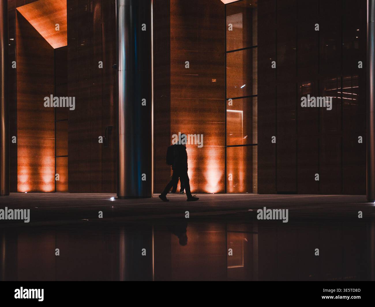Silhouette di un uomo che cammina in città di notte Foto Stock