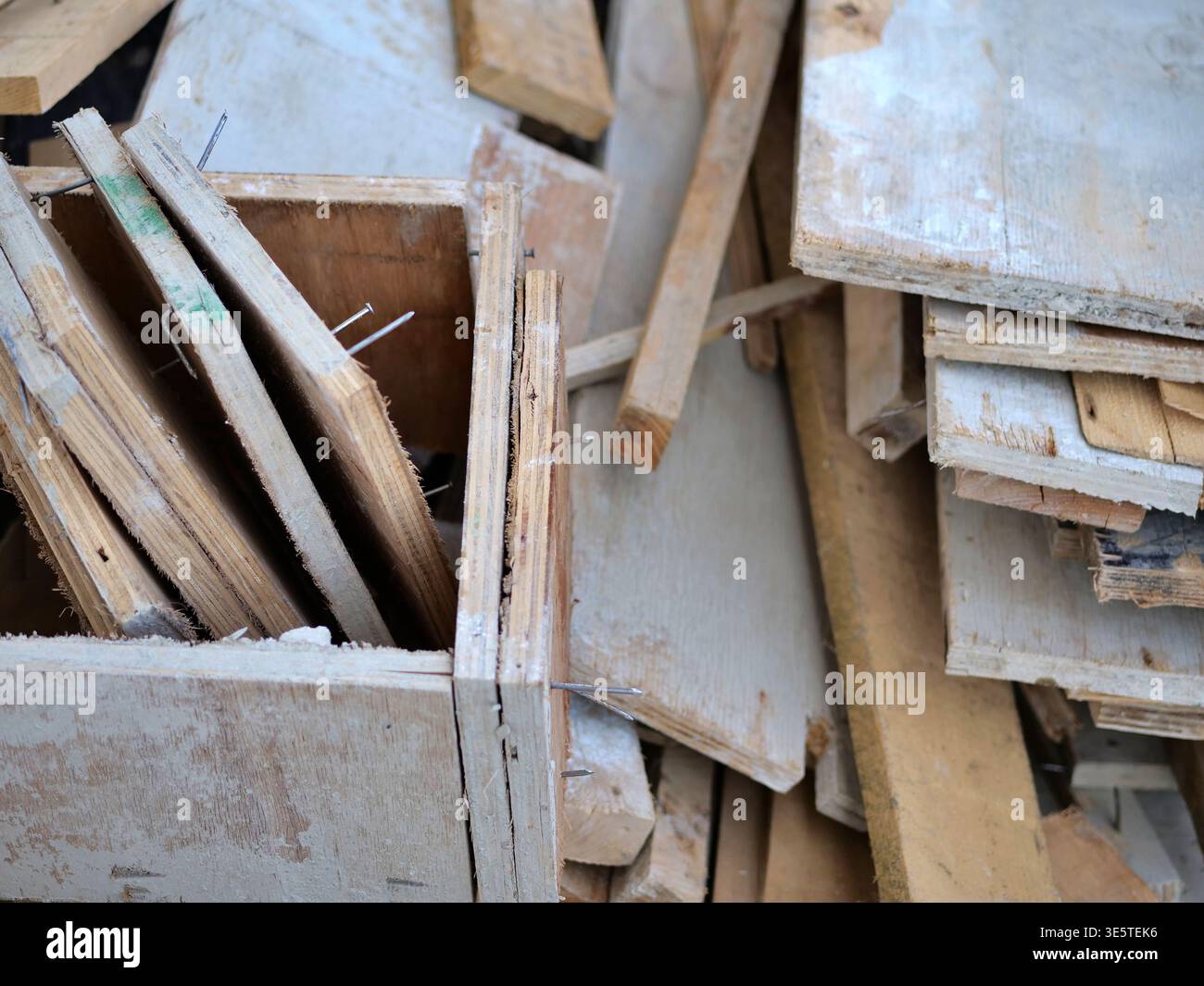 Primo piano di un pavimento piastrellato grigio scuro ricoperto di polvere e detriti di intonaco bianco, scena di ristrutturazione industriale che mostra una pulizia disordinata dopo la demolizione delle pareti Foto Stock