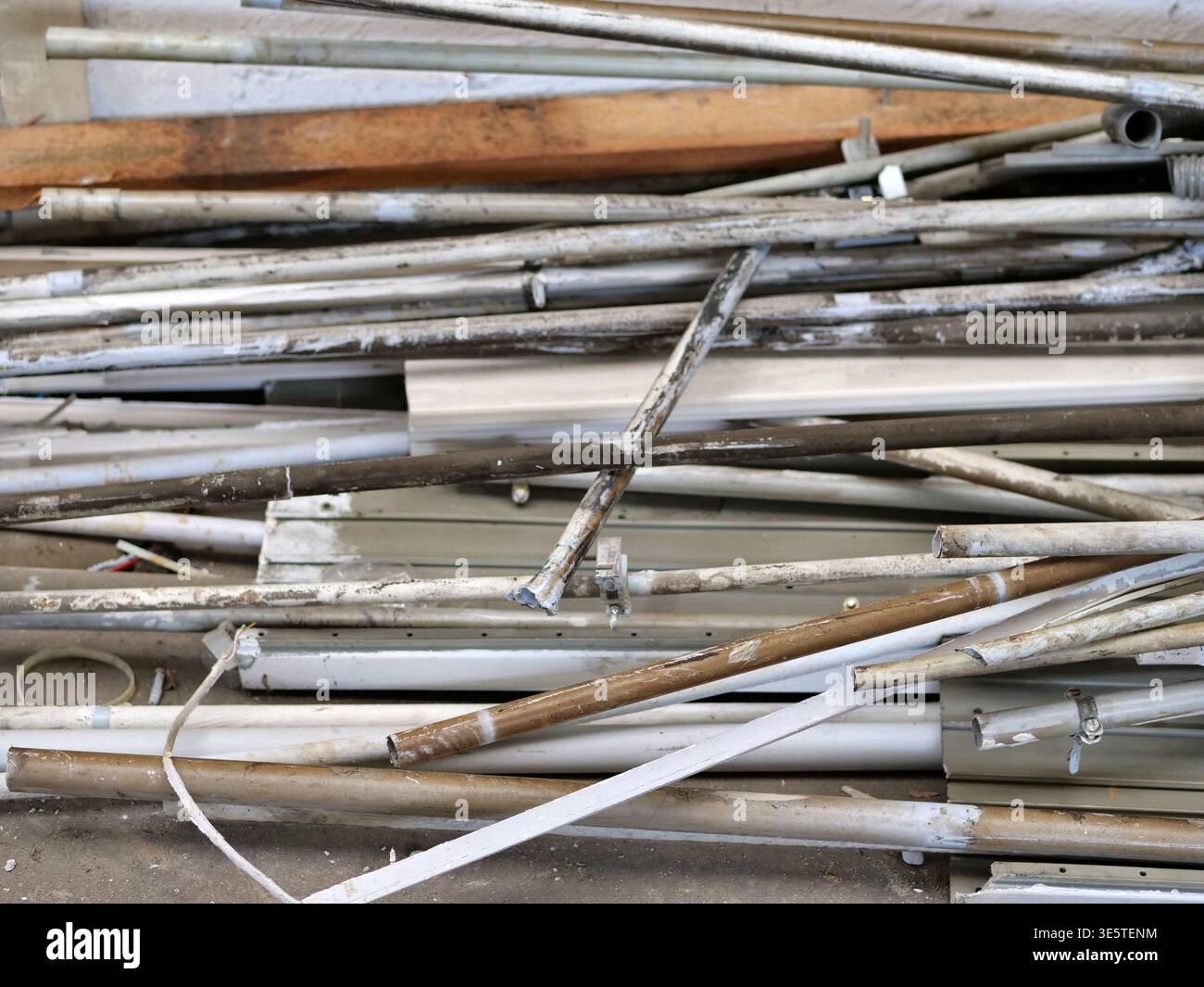 Pile di vecchi tubi luminosi fluorescenti e condotti elettrici in un sito di demolizione, primo piano di lunghe lampade cilindriche in vetro e tubi in plastica scartano Foto Stock