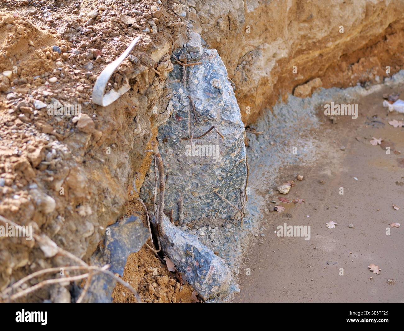 fondazioni in calcestruzzo esposte in trincee di detriti, primo piano di un pilastro in calcestruzzo rotto con arrugginite sotto terra, dettagli del sito di scavo che mostrano la posa del terreno Foto Stock