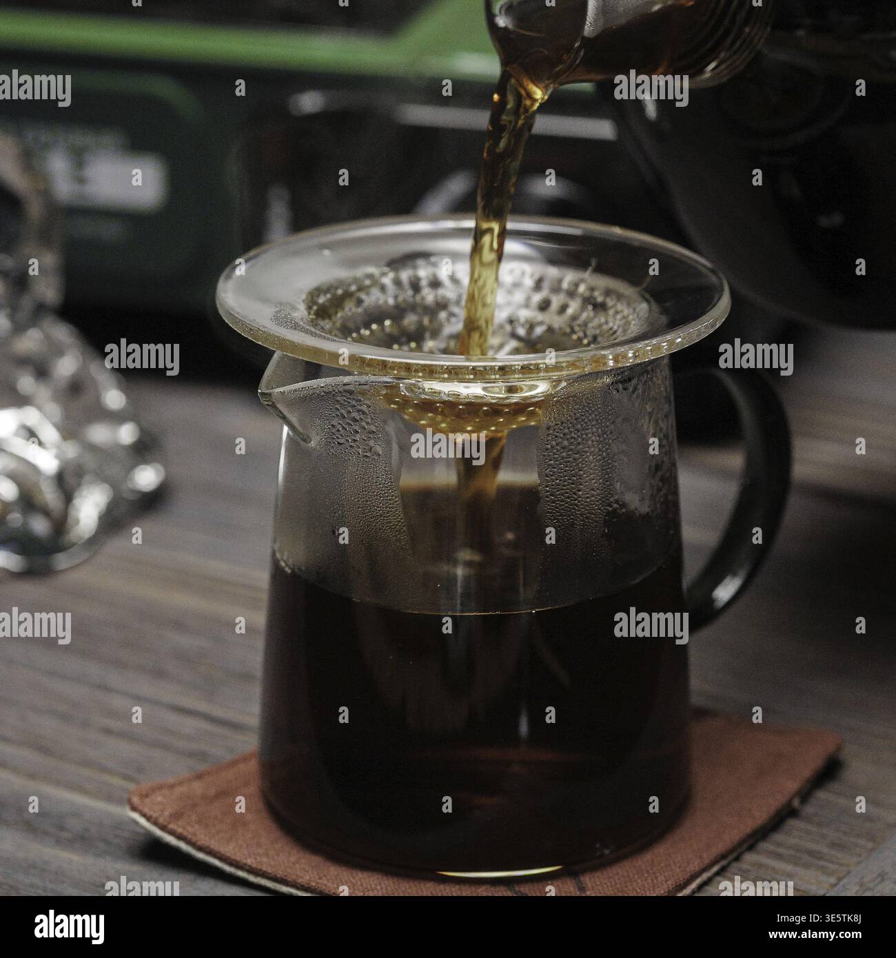 Un primo piano del caffè versato in una caraffa di vetro, che mostra il colore intenso e il processo di erogazione Foto Stock