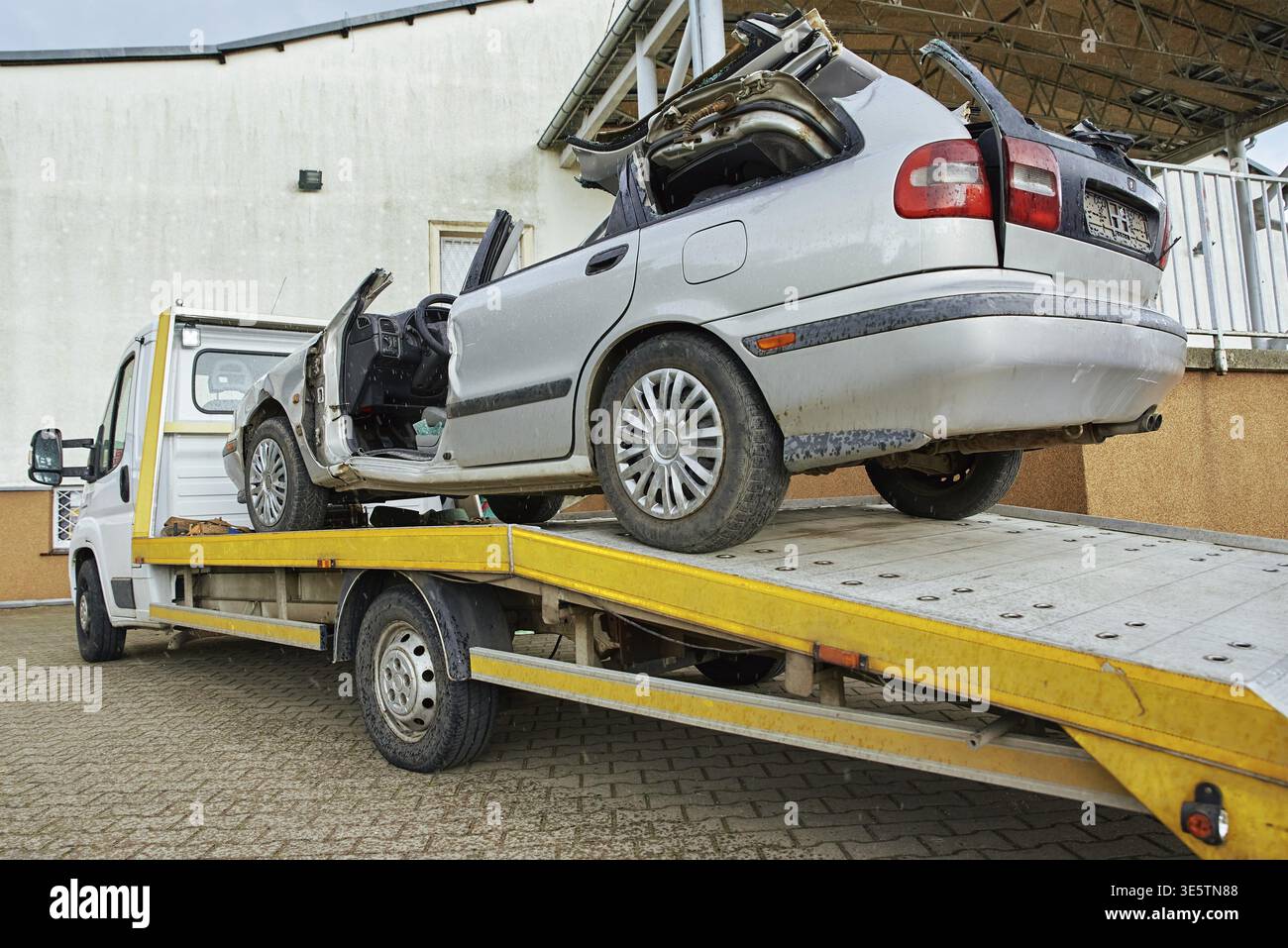 Carico di un'auto distrutta su un autocarro trainato dopo un incidente stradale, concetto di guida pericolosa dopo aver bevuto alcol, concetto di assistenza stradale Foto Stock