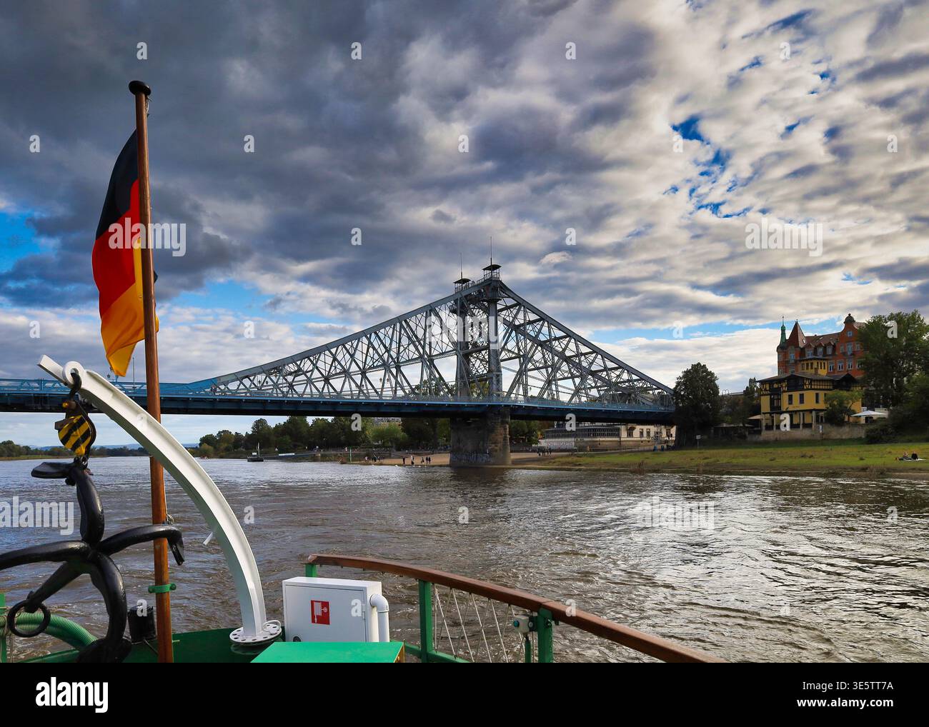 Dresda: Historischer Raddampfer auf der Elbe vor dem Blauen Wunder – Perspektive vom Heck mit Deutschlandfahne und Seilrolle, Sachsen Foto Stock