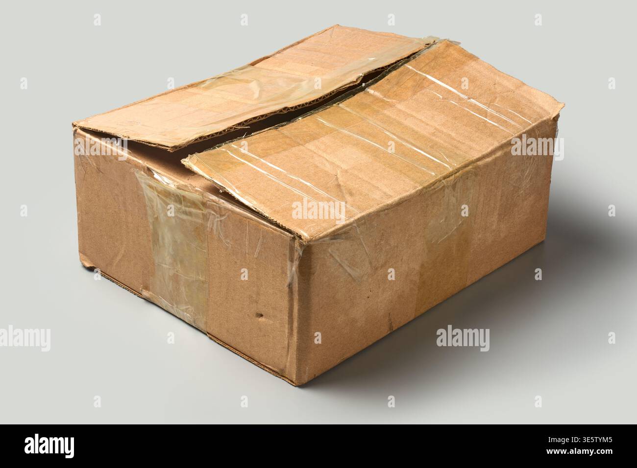 scatola di cartone marrone chiusa usata, sfondo grigio isolato, cartone di spedizione con nastro adesivo trasparente, vista angolare Foto Stock