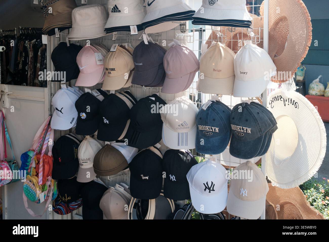 I tappi multipli sono appesi al rack display. Sono visibili diversi colori e stili. Alcuni berretti hanno scritte ricamate. I cappucci sono disposti per una facile visualizzazione Foto Stock