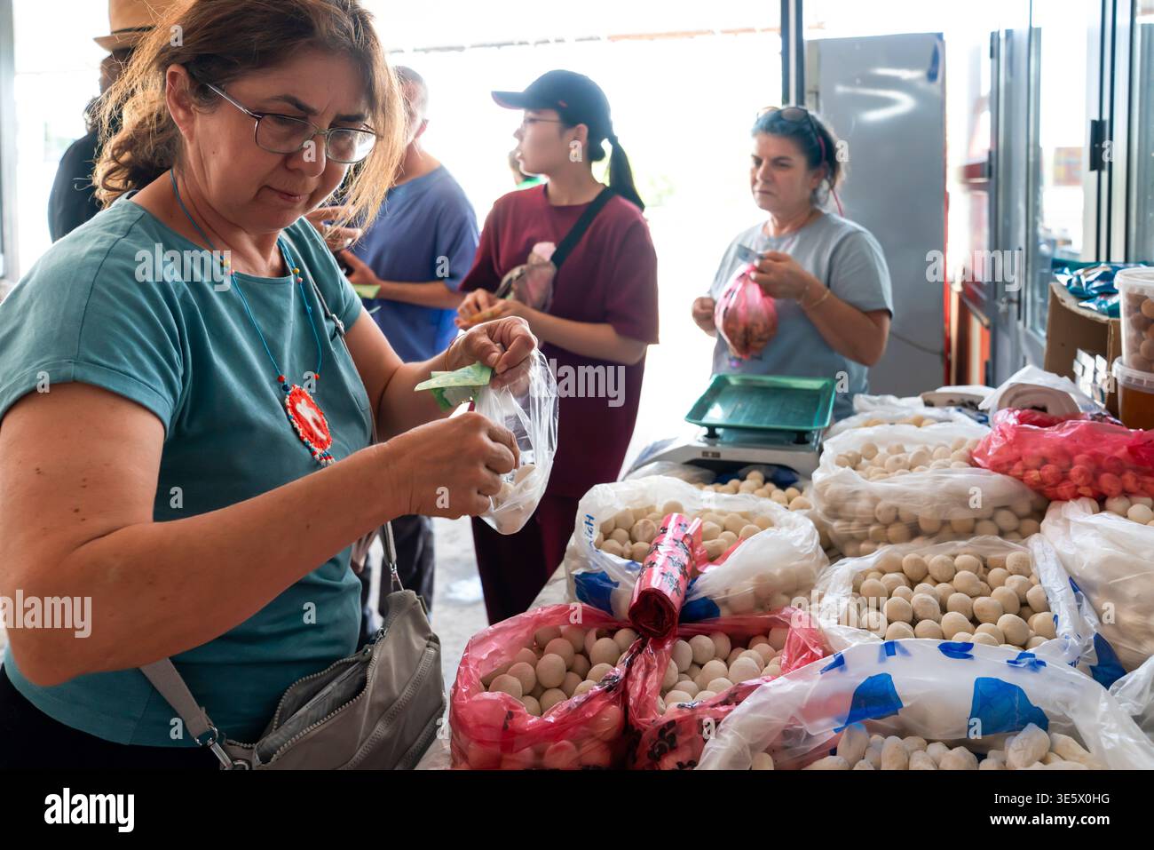Turkistan, Kazakistan - 2 giugno 2025: Momento sincero di una donna turistica che acquista palle di yogurt secco al qurt tradizionale in un mercato sulla strada per T Foto Stock