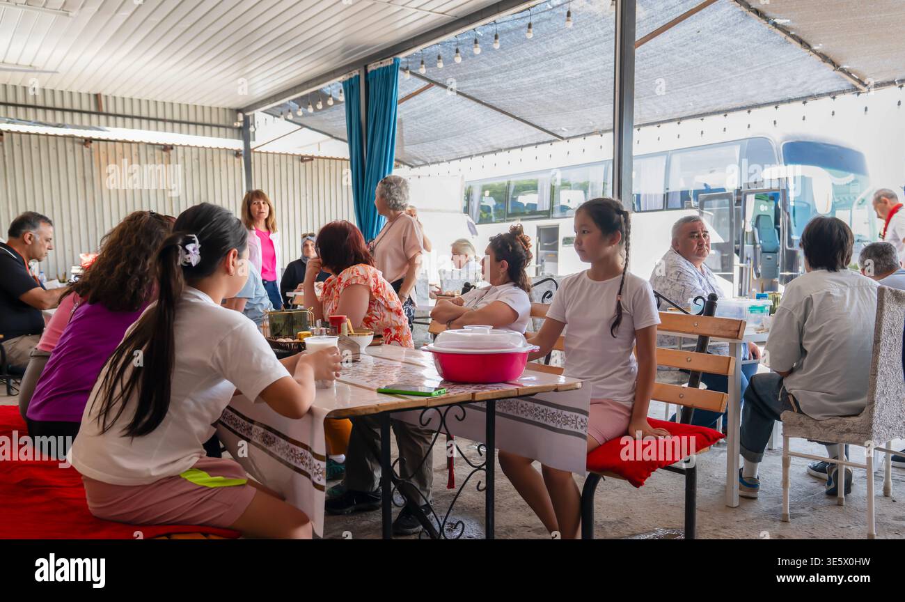 Kazakistan - 2 giugno 2025: Momento sincero di gente locale e turisti kazaki che cenano insieme a una fermata lungo la strada durante un autobus mola sulla strada per Turkis Foto Stock