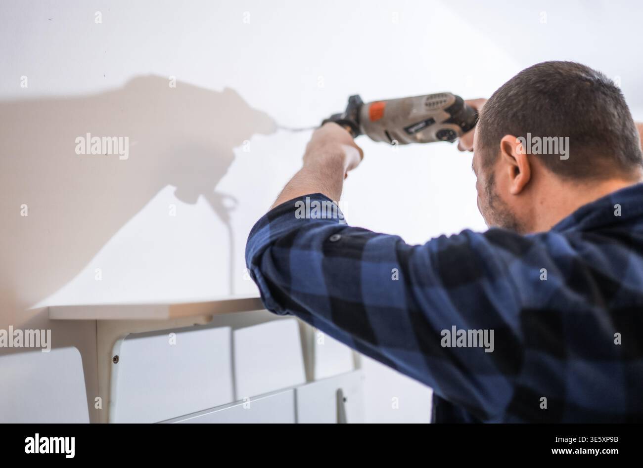 Manoile che perfora fori per staffe da parete per scaffali, assemblaggio professionale di mobili e progetto di manutenzione domestica. Foto Stock