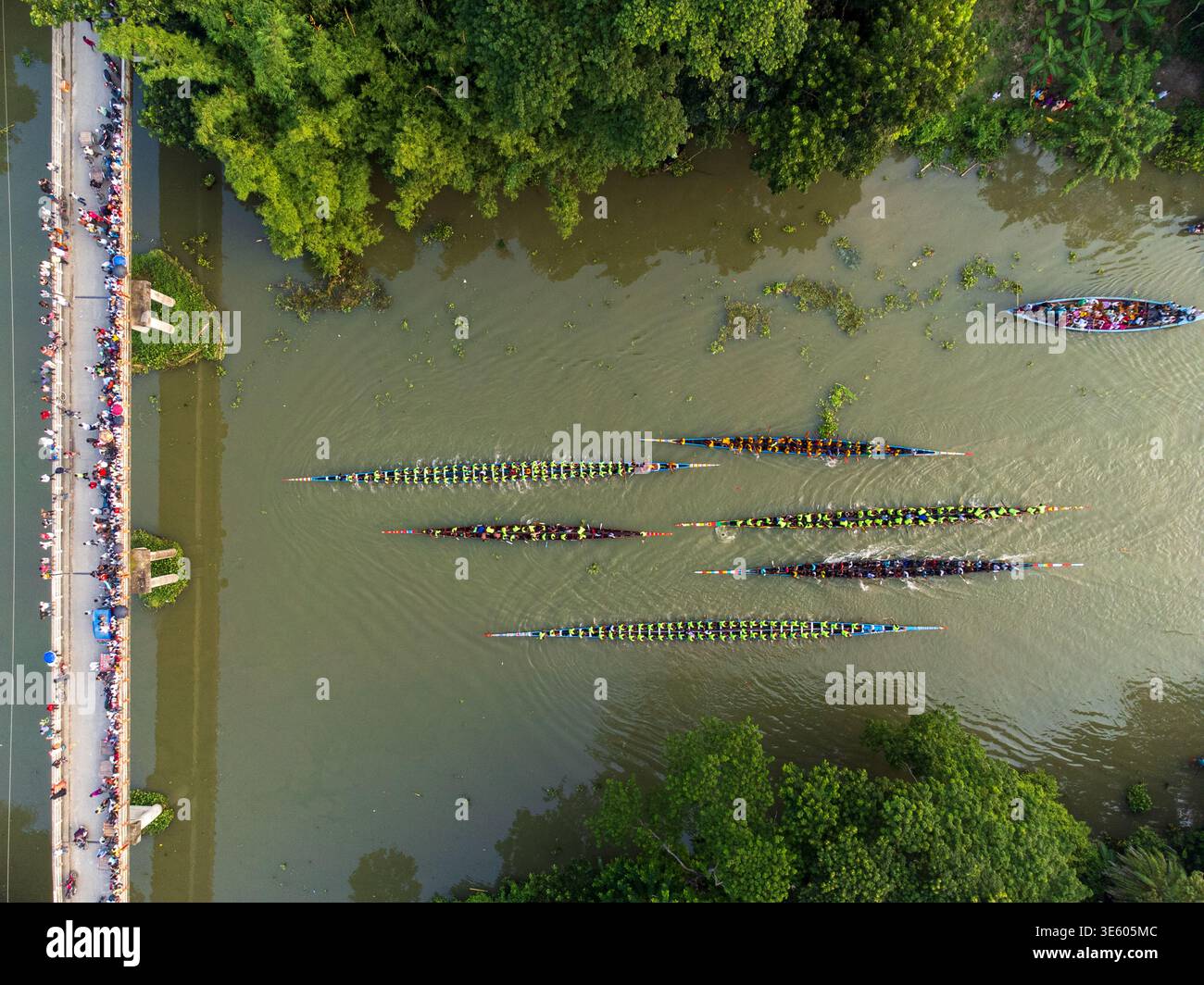 Veduta aerea della vivace corsa di barche che attraversa il torbido fiume, mentre gli spettatori affollano il ponte, Gopalganj, Divisione di Dacca, Bangladesh. Foto Stock