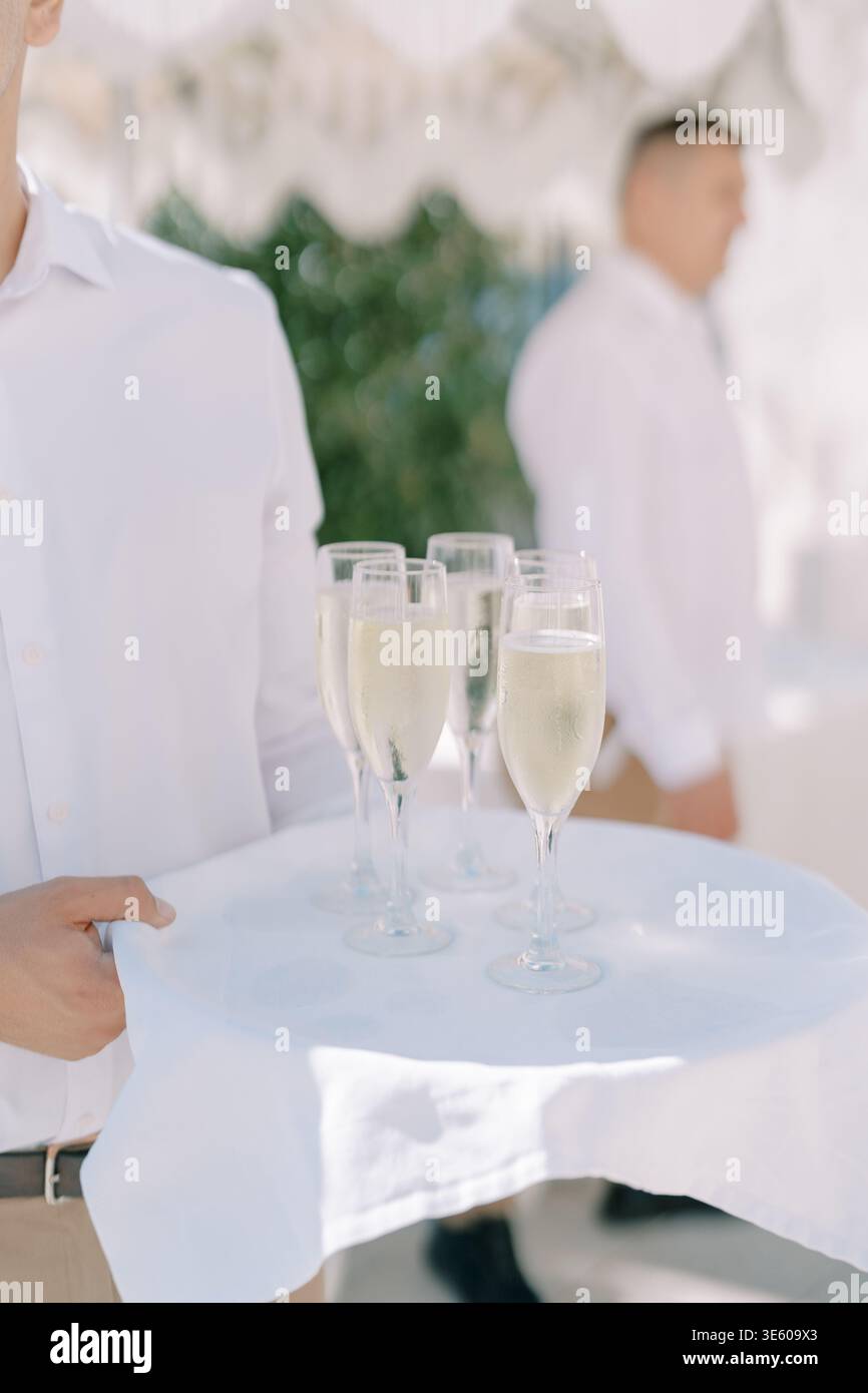 Catering professionale che propone bevande sotto il tettuccio della tenda illuminata dal sole Foto Stock