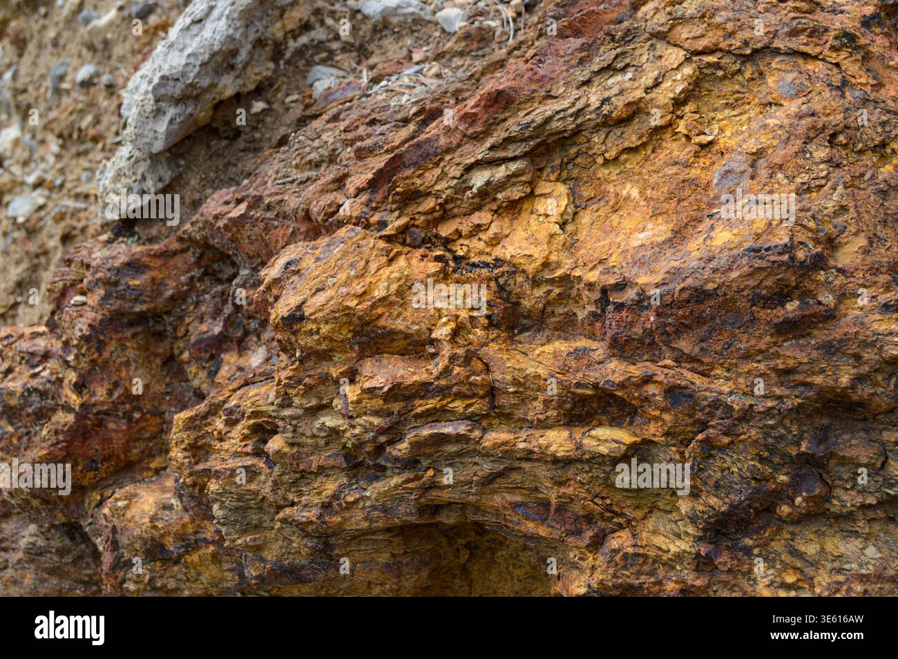 Superficie rocciosa intemprata con depositi minerali ossidati e struttura geologica stratificata Foto Stock