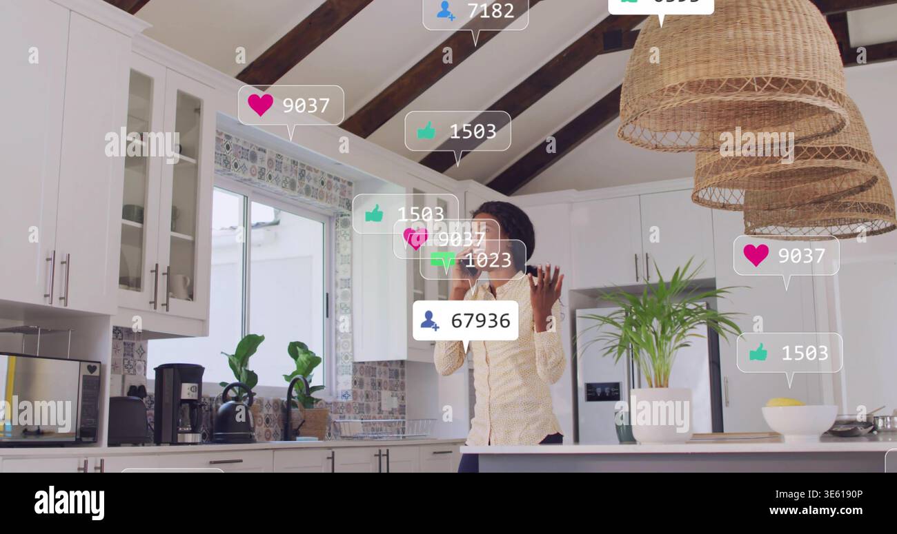 Con smartphone, donna che indossa una camicetta leggera e pantaloni scuri che gestiscono in cucina, sovrapposizioni sociali Foto Stock