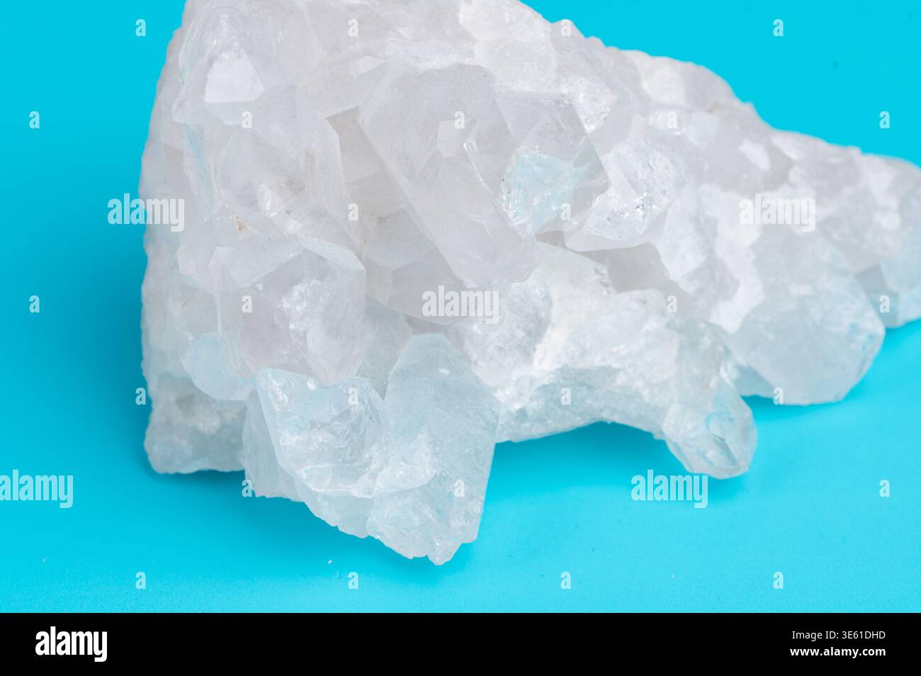 Un pezzo di cristallo di roccia trasparente è posizionato su una superficie blu Foto Stock