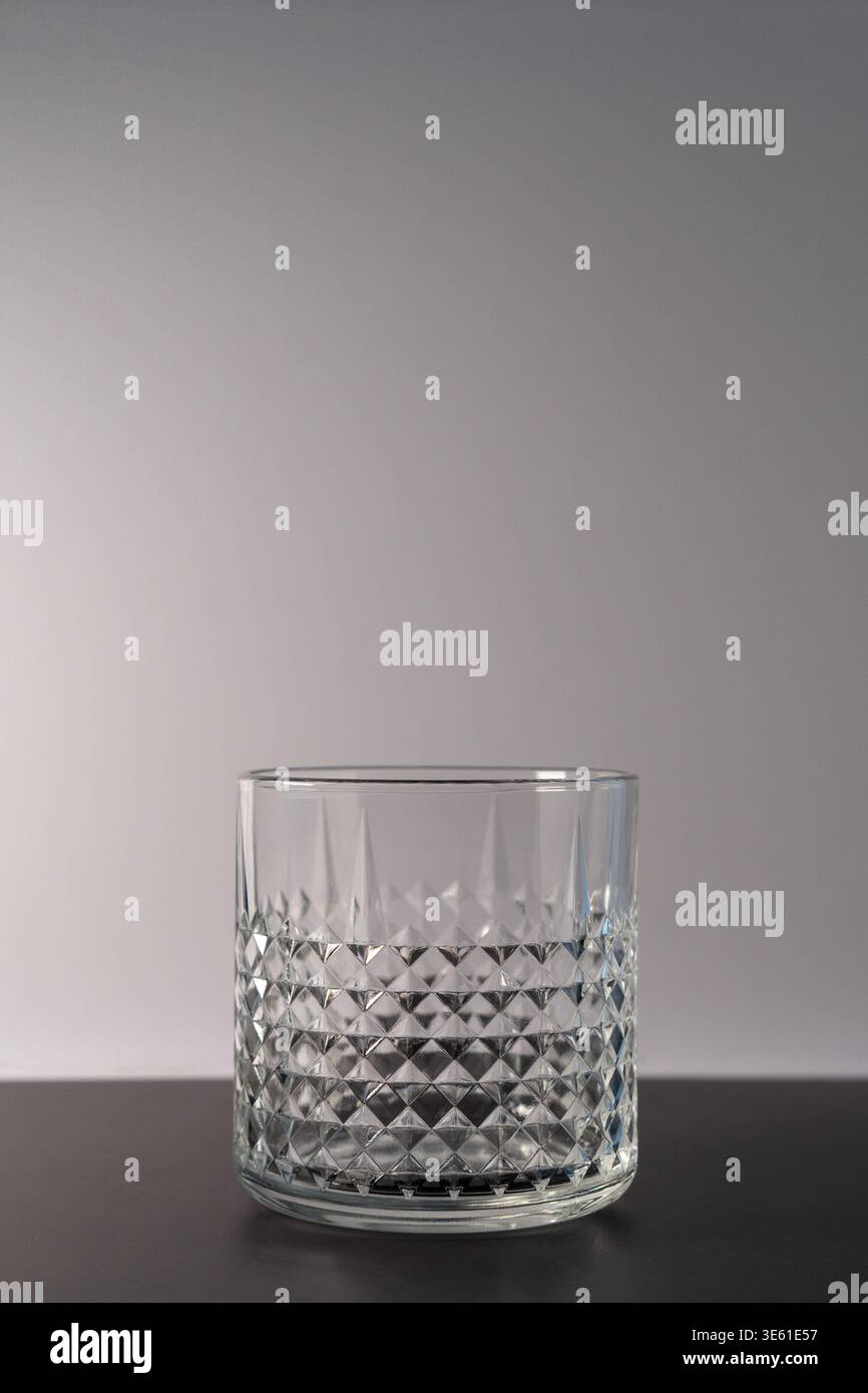 Immagine verticale di un bicchiere di whisky vuoto isolato su una superficie nera con sfondo bianco Foto Stock
