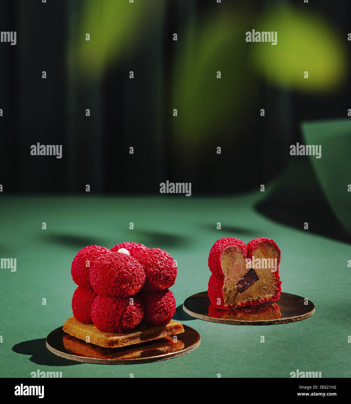 Cibo, due squisiti dessert seduti su superfici riflettenti in una pasticceria. Ogni delicatezza presenta colori vivaci e design intricati, che mettono in risalto la bellezza Foto Stock