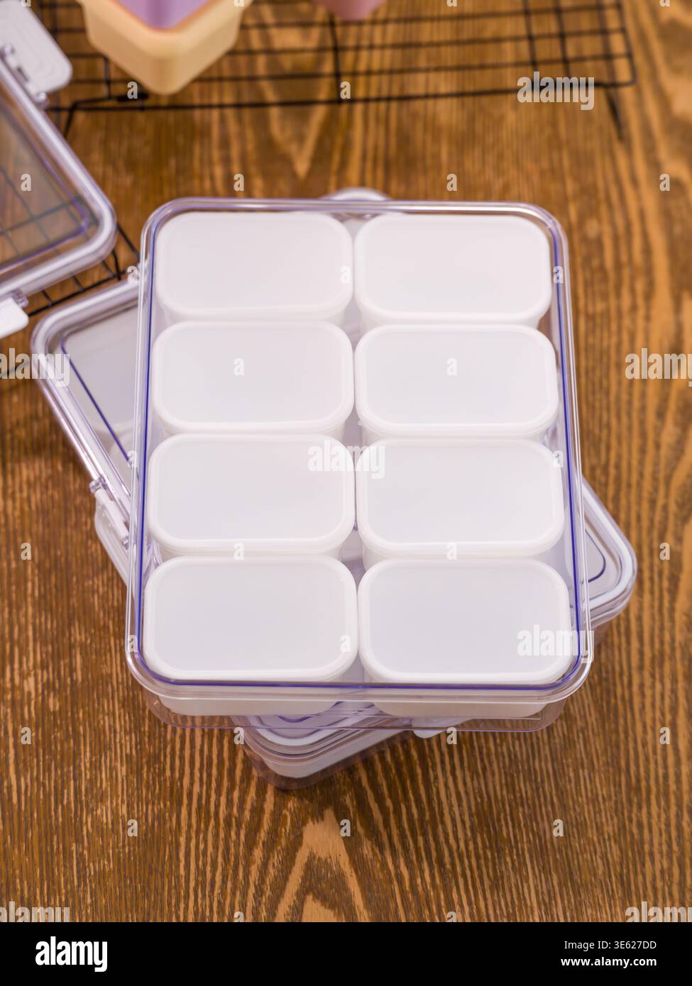 Una custodia in plastica trasparente contiene otto piccoli contenitori quadrati bianchi per la conservazione degli alimenti in una griglia ordinata 2 per 4. Foto Stock