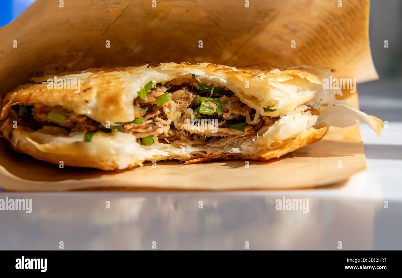 Primo piano di un Roujiamo o hamburger cinese della provincia di Shannxi, Cina. Il panino è un pane piatto croccante a più strati, con il classico ripieno di Foto Stock