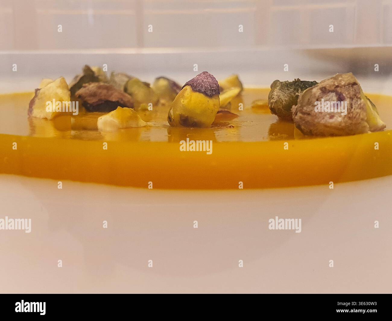 Una foto macro di primo piano che mostra diversi elementi organici secchi di forma irregolare che poggiano su o parzialmente sommersi in una piscina di color ambra Foto Stock