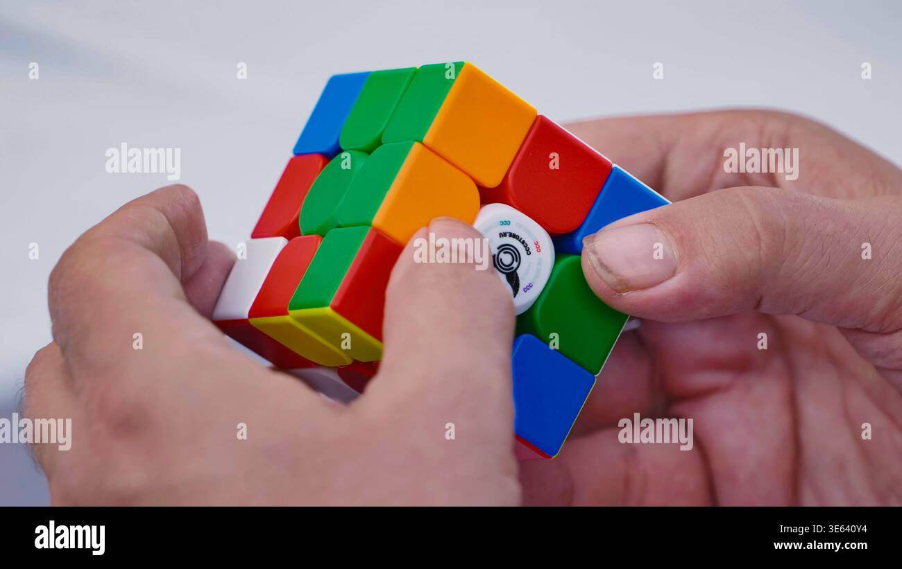 Mosca, Russia - 5 luglio 2025: Mani che risolvono il cubo colorato di Rubik, il gioco di logica e la sfida intellettuale Foto Stock