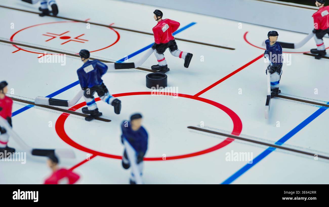 Un primo piano dinamico di una classica partita di hockey da tavolo con giocatori rossi e blu Foto Stock