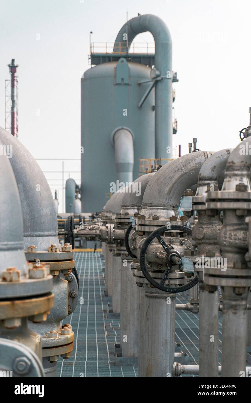 Grande impianto industriale con numerosi tubi e valvole. Le valvole sono tutte nere e i tubi sono argentati Foto Stock