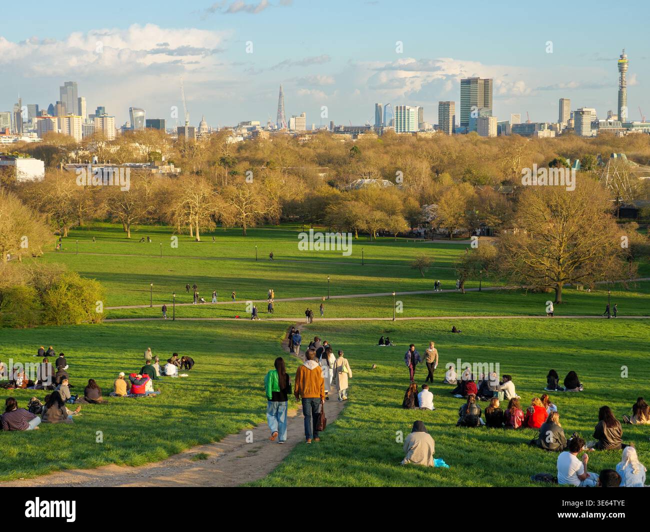 Giovani seduti sull'erba e che guardano lo skyline della città in cima al parco Primrose Hill, Londra, Regno Unito Foto Stock