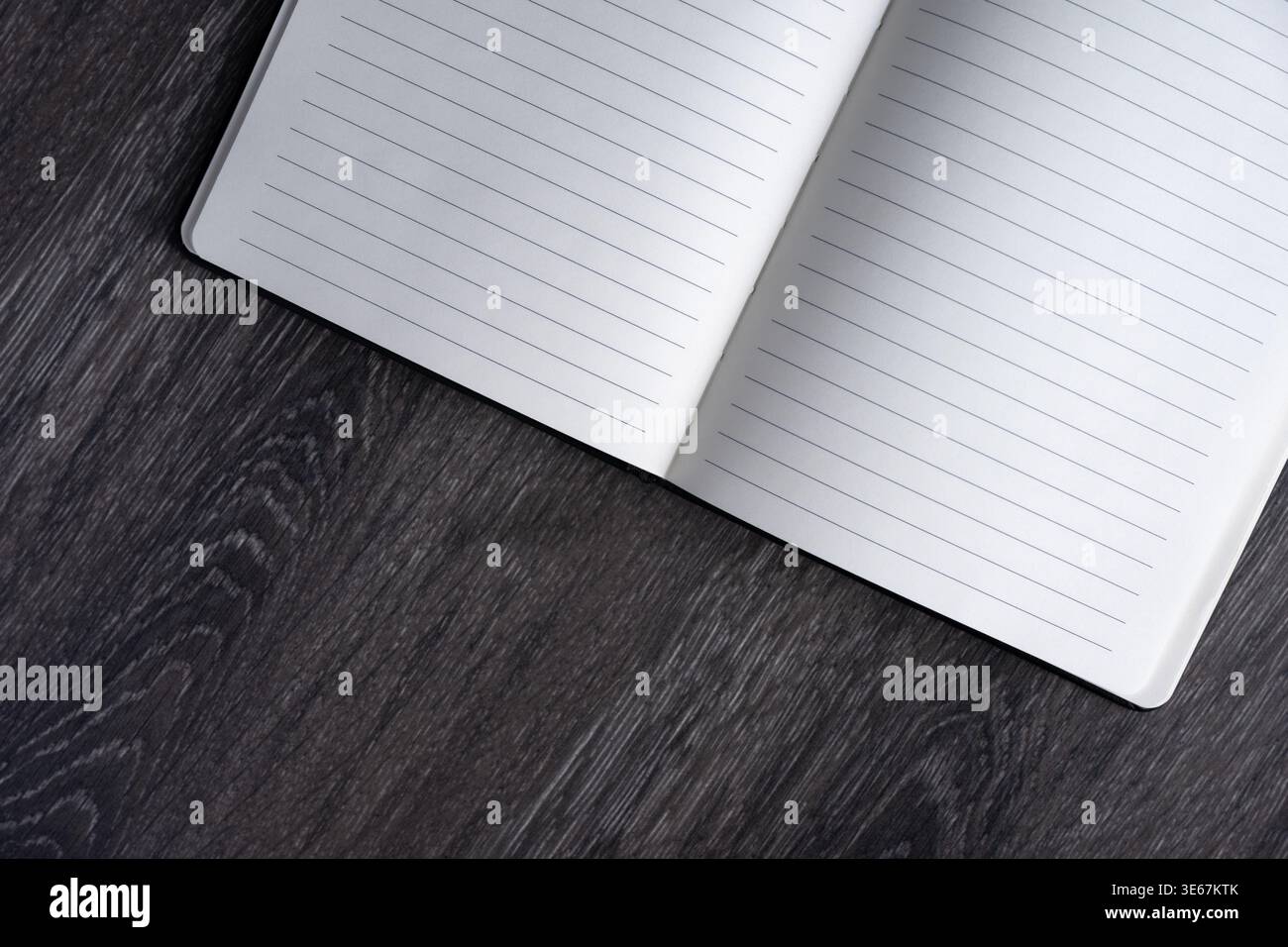 Notebook aperto rivestito in bianco su una scrivania in legno con spazio per le copie. Concetto minimo di spazio di lavoro per scrittura, pianificazione, inserimento nel Journal e produttività. Foto Stock