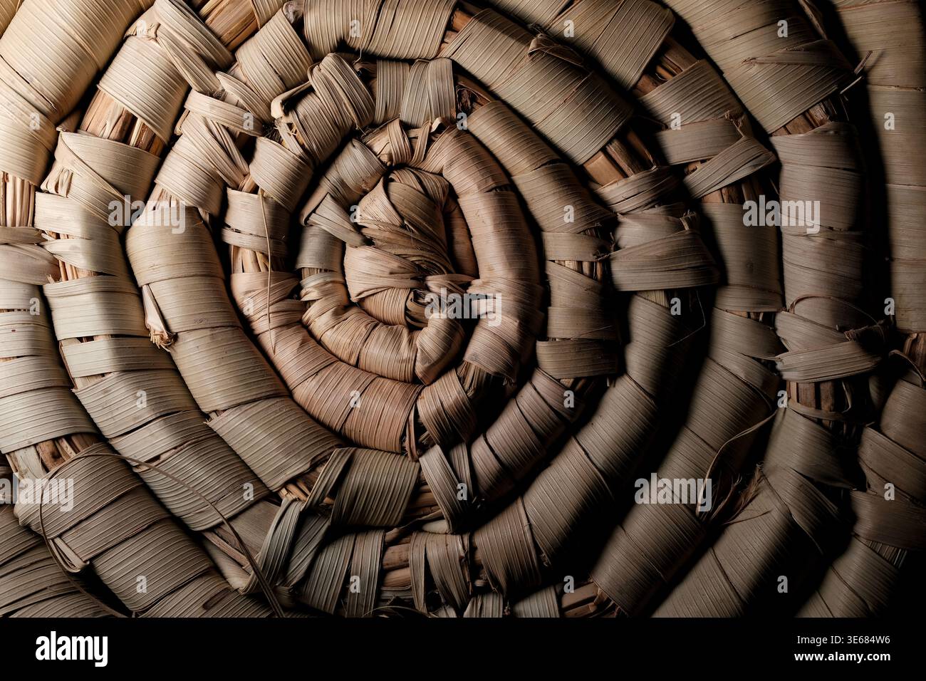 Spirale ravvicinata di fibre di palma o paglia essiccate tessute che formano un tappeto rustico arrotolato con strisce sovrapposte testurizzate in calde tonalità marroni Foto Stock