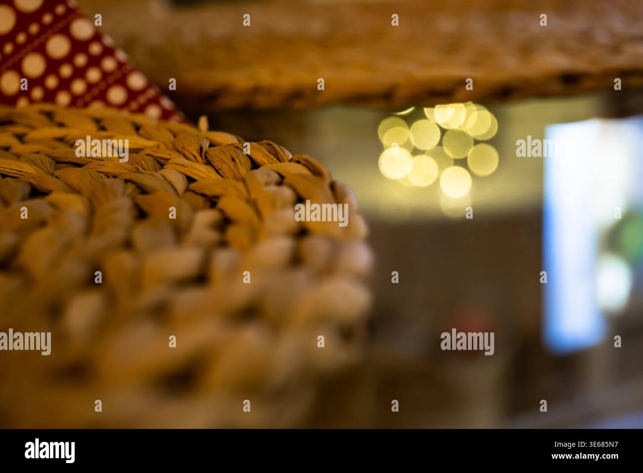 primo piano di un sottobicchiere intrecciato su un tavolo con sfocature in primo piano e riflessi di luce bokeh sullo sfondo Foto Stock