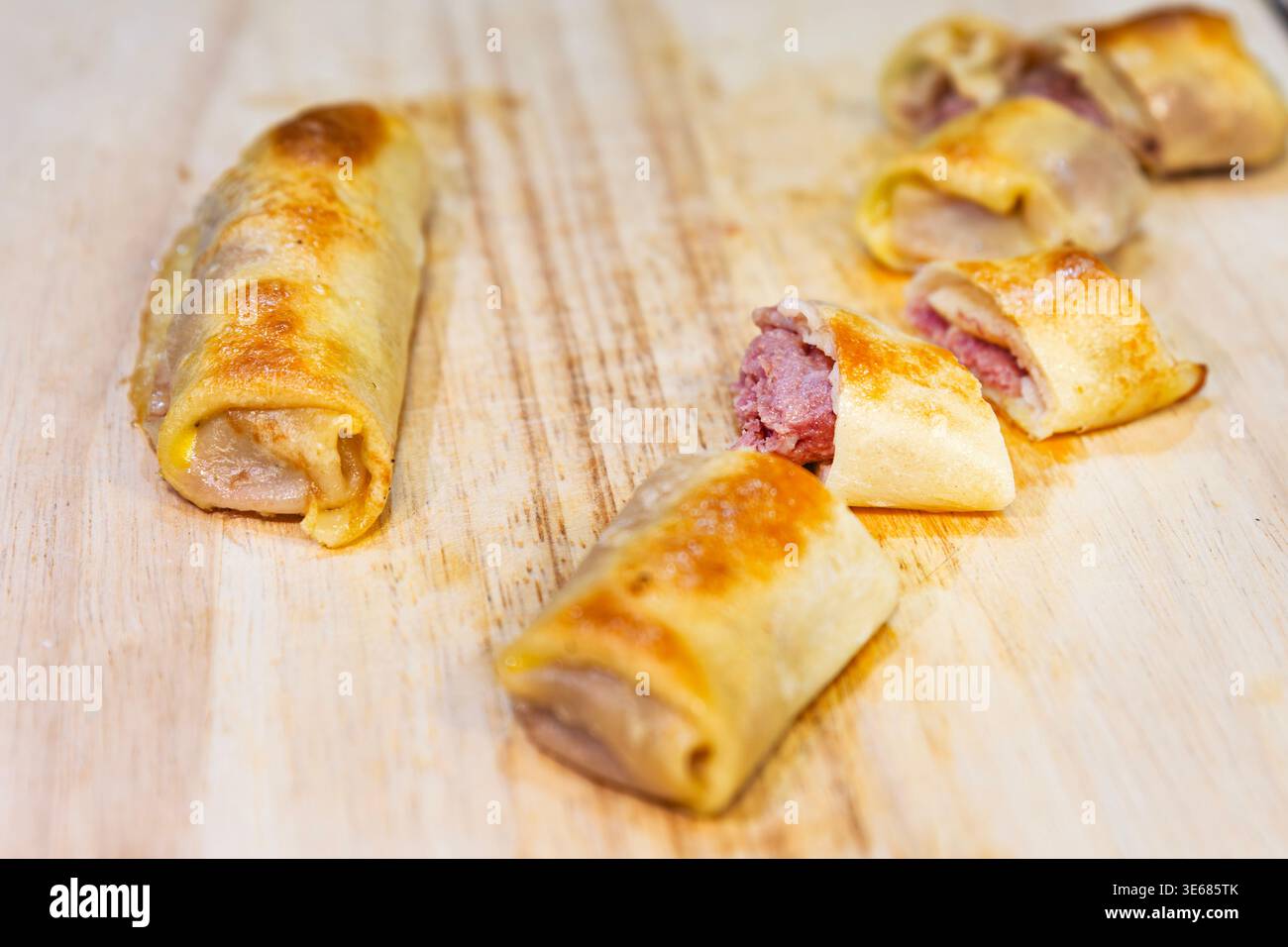 Deliziosi rotoli di crepe fritti con ripieno di carne macinata su legno Foto Stock