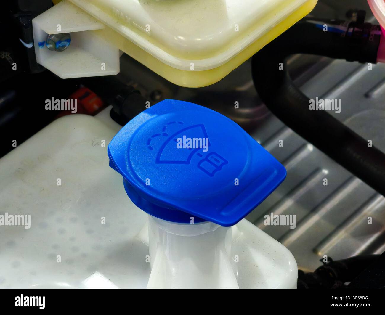 Primo piano del tappo blu del serbatoio del liquido lavavetro all'interno di un vano motore di un'auto moderna. Questa immagine rappresenta la manutenzione ordinaria del veicolo e il veicolo Foto Stock