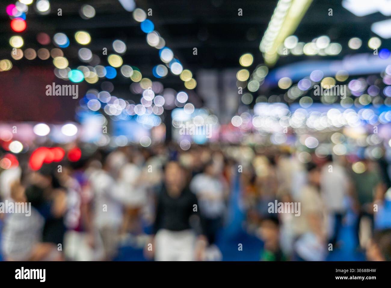 Sfondo astratto sfocato di una grande folla che partecipa a una grande fiera o a una fiera dell'automobile. Presenta luci bokeh colorate e un'atmosfera vivace in una zona spaziosa Foto Stock