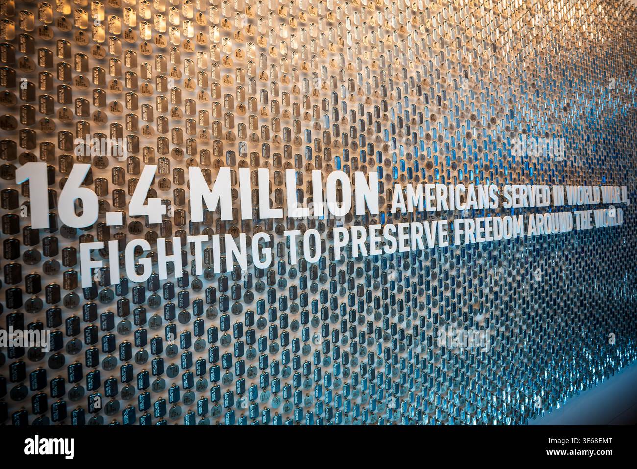 National World War II Museum Dog Tag Wall Display New Orleans Stati Uniti | NEW ORLEANS, Louisiana — Un grande espositore murale al National WWII Museum presenta migliaia di targhette militari sospese dietro lettere bianche rialzate che onorano i 16,4 milioni di americani che hanno servito nel conflitto. Originariamente fondato come National D-Day Museum, questa istituzione designata dal Congresso utilizza il volume impressionante di targhette di identificazione riprodotte per quantificare visivamente la scala massiccia della mobilitazione militare degli Stati Uniti tra il 1941 e il 1945. Standardizzate durante la guerra, queste targhette di metallo w Foto Stock