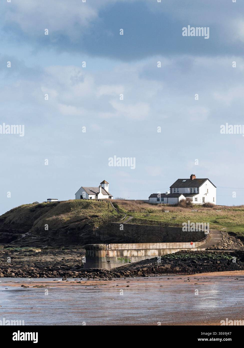Vista dalla spiaggia di Seaton a Northumberland, Regno Unito, verso il molo e la casa di osservazione con la bassa marea. Foto Stock
