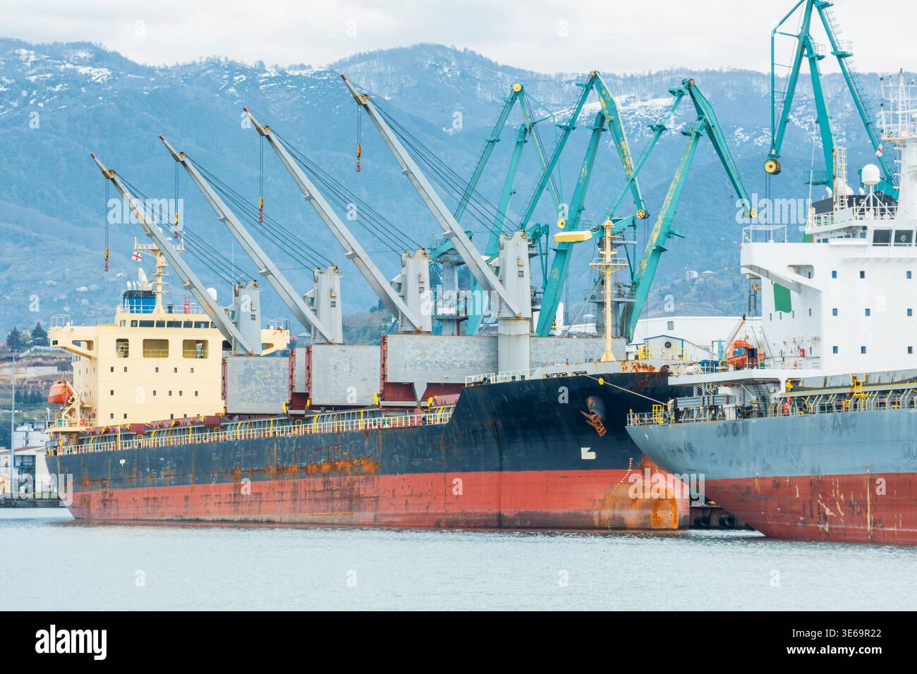 Navi da carico attraccate al porto di Batumi con gru che gestiscono le operazioni di carico e scarico. Logistica marittima, infrastrutture di trasporto e trasporti Foto Stock