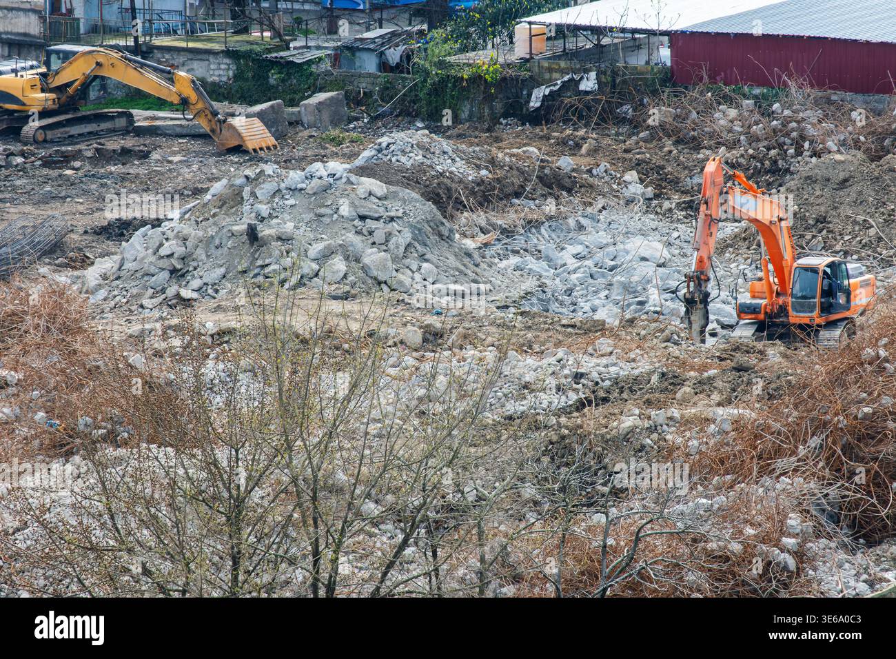 Escavatore con demolitore idraulico per la demolizione del calcestruzzo in cantiere. Macchinari pesanti che frantumano i detriti ed eseguono operazioni di pulizia del terreno Foto Stock