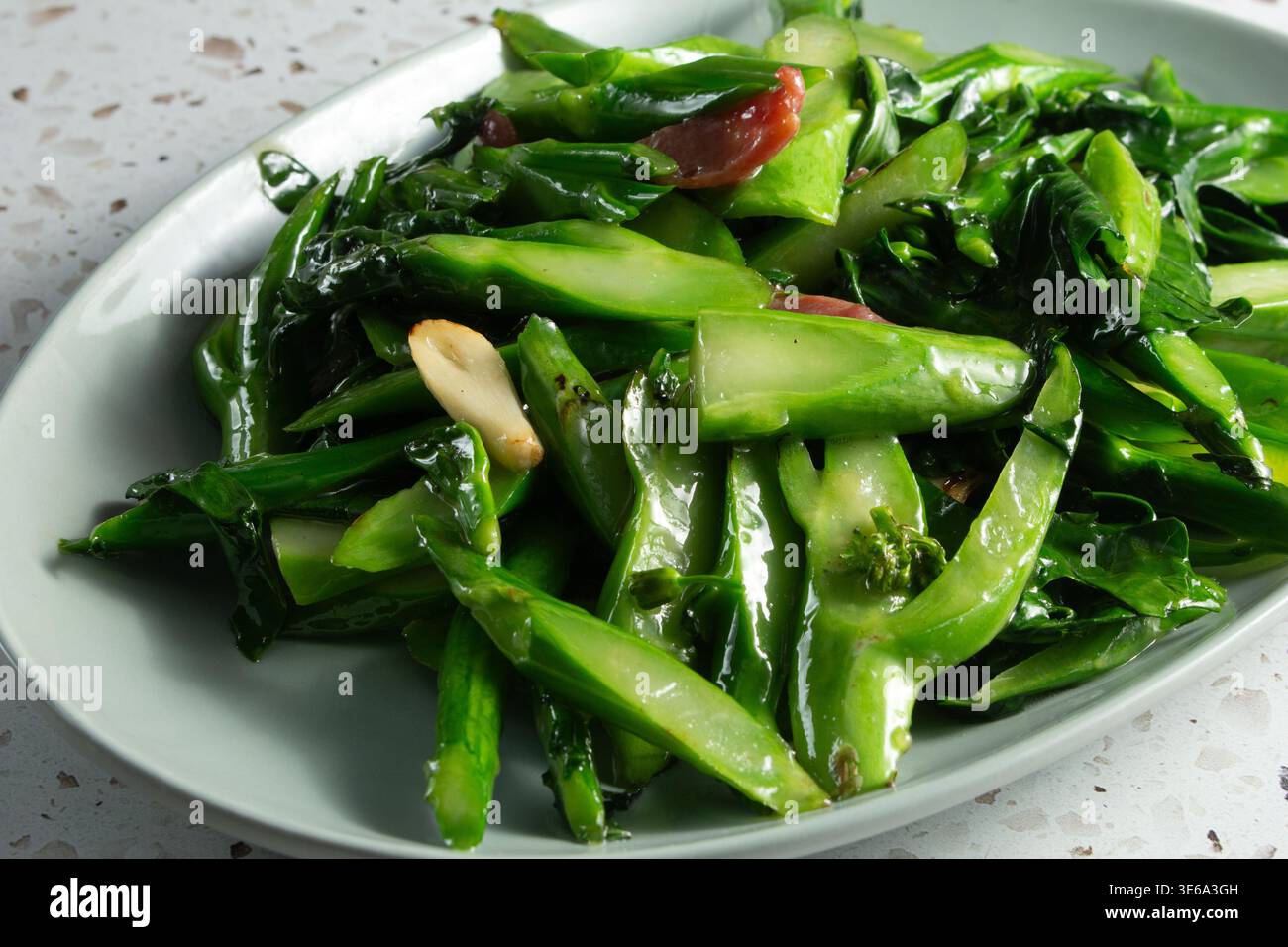 Vista ravvicinata di un piatto di gai lan fritti in padella e salsiccia. Foto Stock