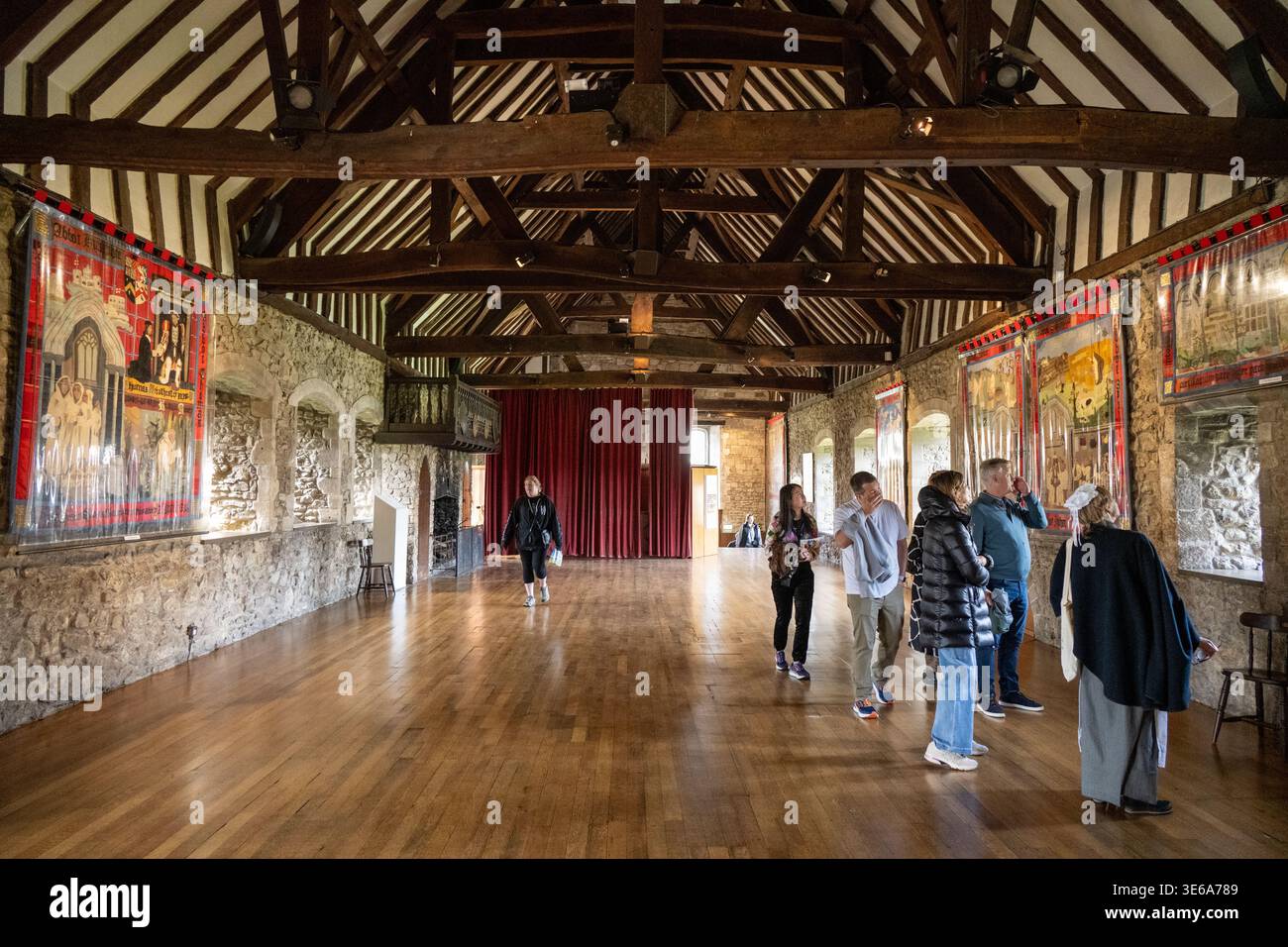 Beaulieu, Regno Unito - 12 aprile 24: Visitatori all'interno di una grande sala storica con pareti in pietra, tetto in legno e arazzi a Beaulieu, Hampshire, Inghilterra. Foto Stock