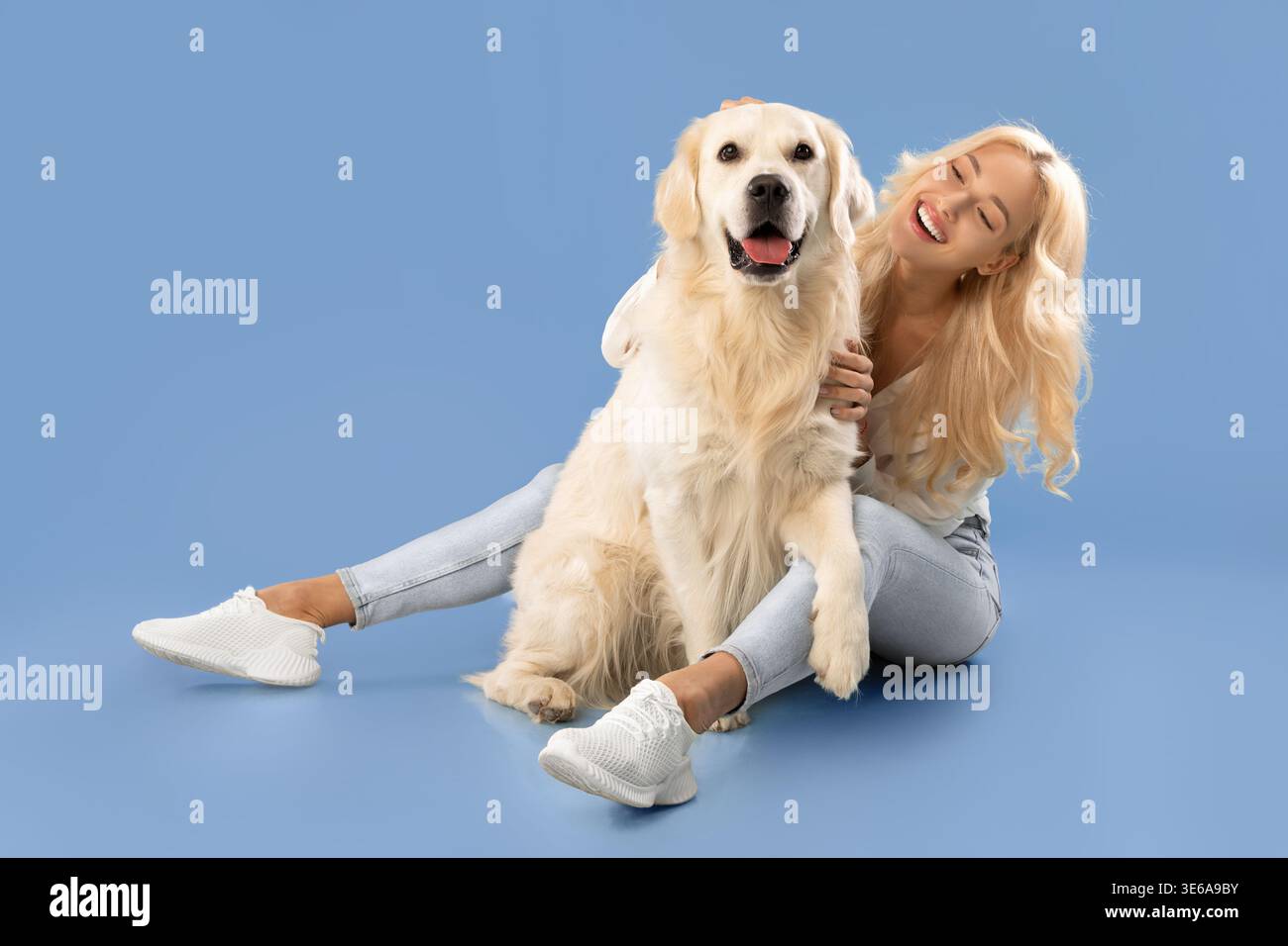 Una donna siede sul pavimento con Golden Retriever Dog e Smiles Foto Stock
