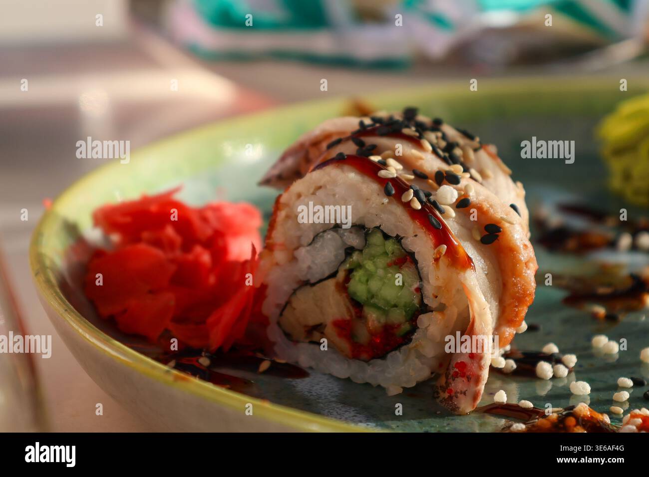 I sushi Rolls sono posti su un piatto verde insieme a wasabi e zenzero sottaceto in un ristorante durante il pranzo, mostrando ingredienti e colori diversi. Foto Stock